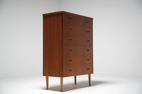 A teak tall boy chest of drawers.